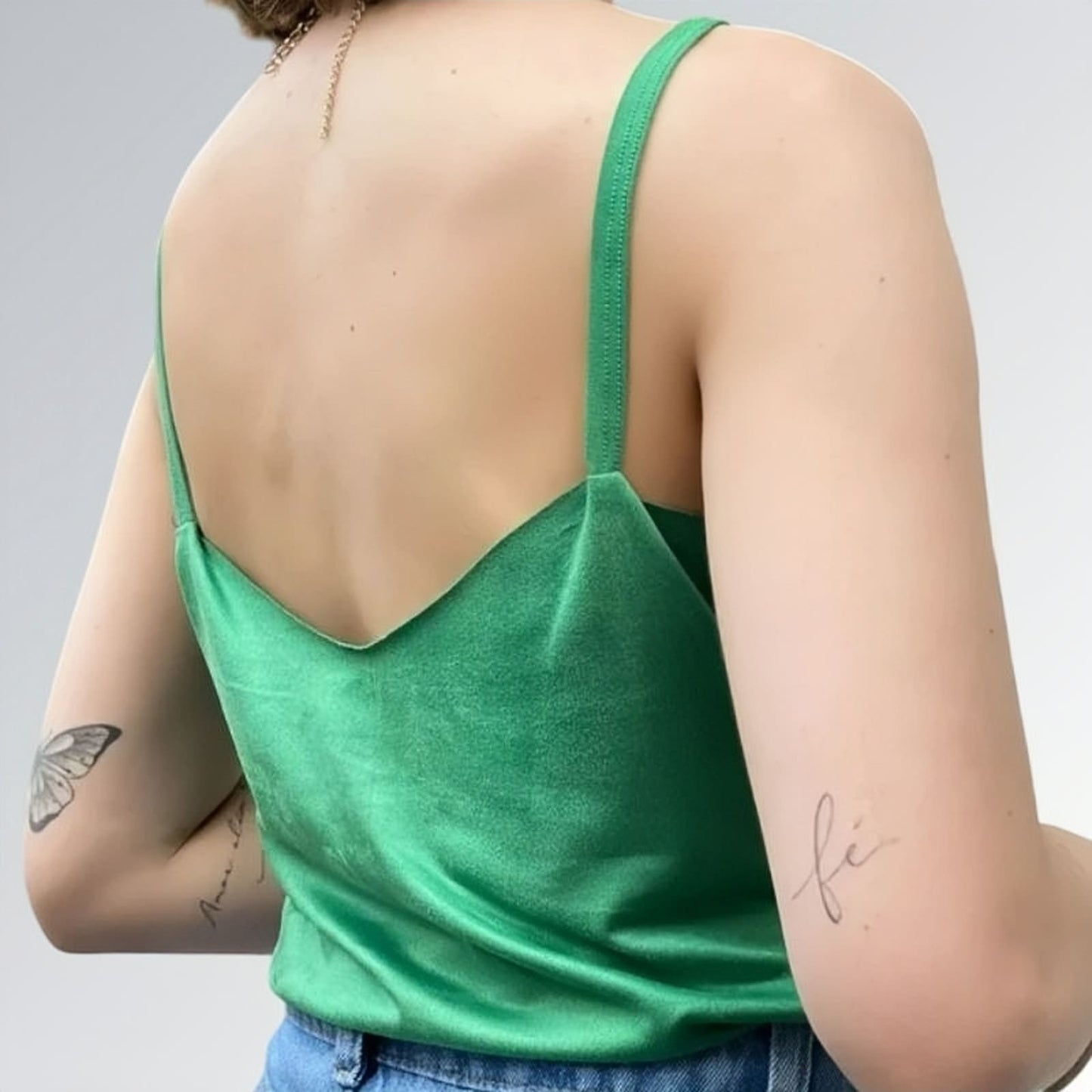 Blusa regata veludo estilo sueco feminina verde com alças finas, combinada com calça jeans azul clara e acessórios minimalistas — peça moderna disponível para venda online de moda casual.