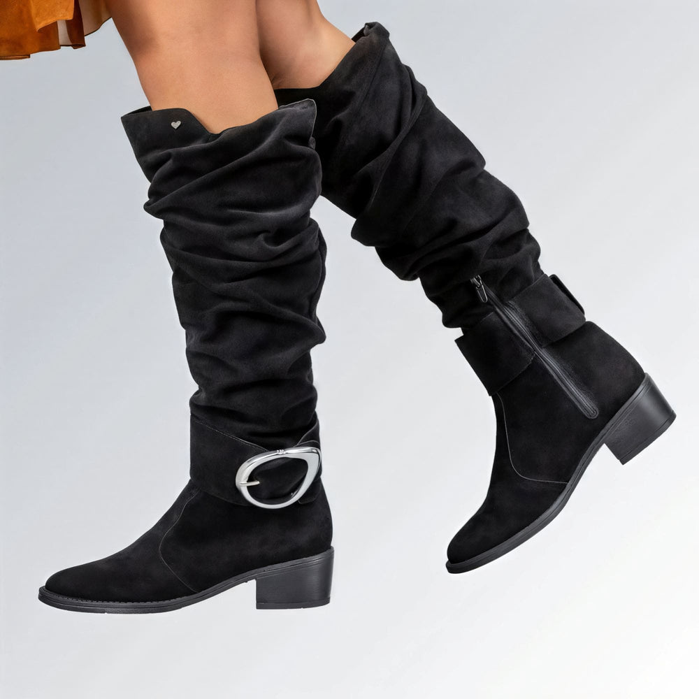 Bota feminina GuGi em camurça preta, cano alto acima do joelho com detalhe de fivela e salto baixo.