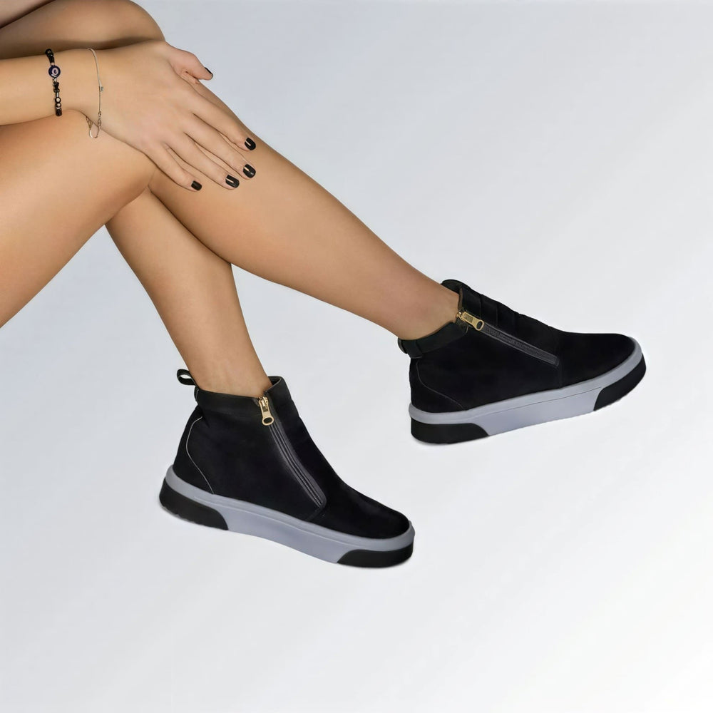 Bota feminina GuGi estilo Knot em camurça preta, com sola plana branca, zíper lateral e design moderno.