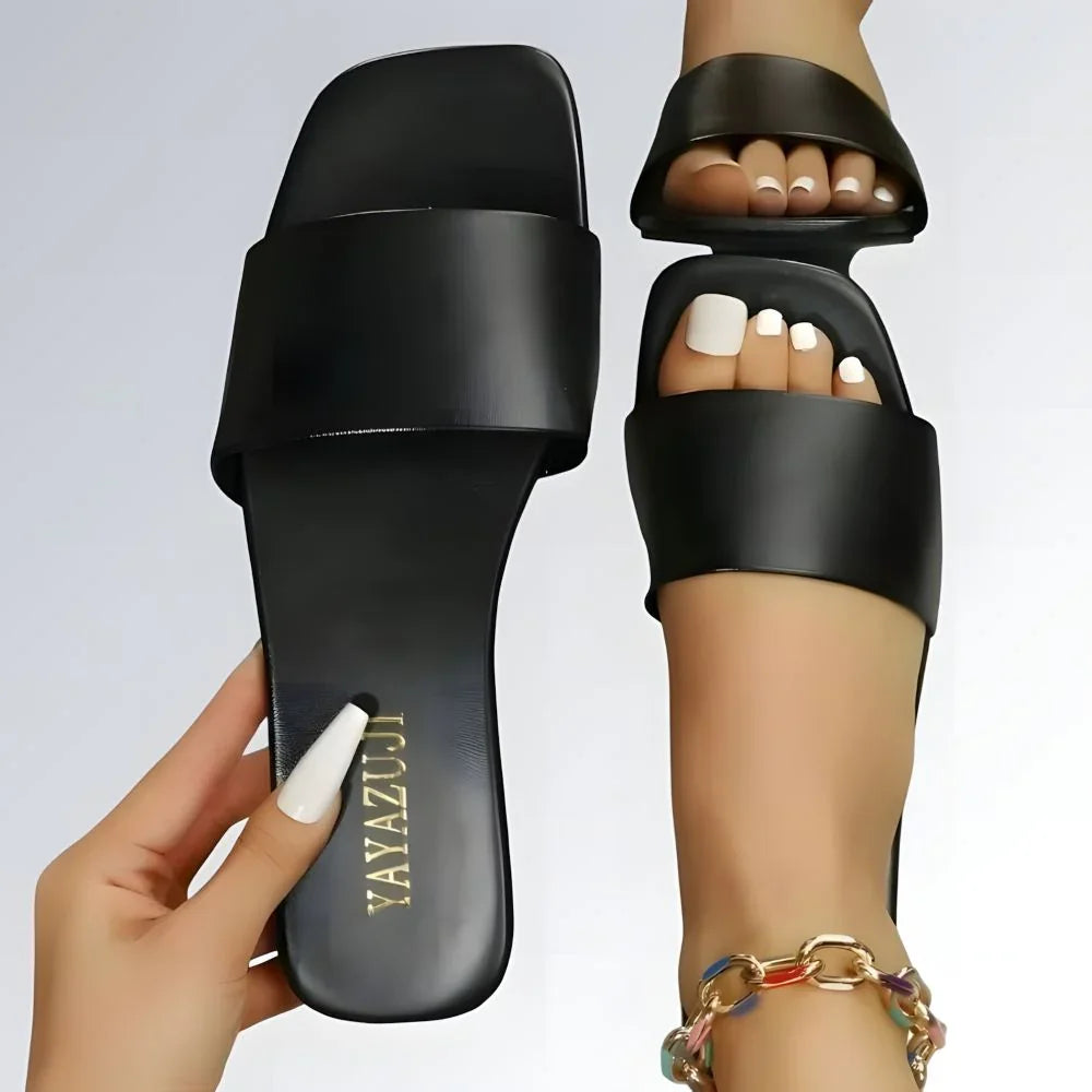 Rasteirinha feminina preta estilo slide com tira larga, design minimalista e detalhe dourado na palmilha.