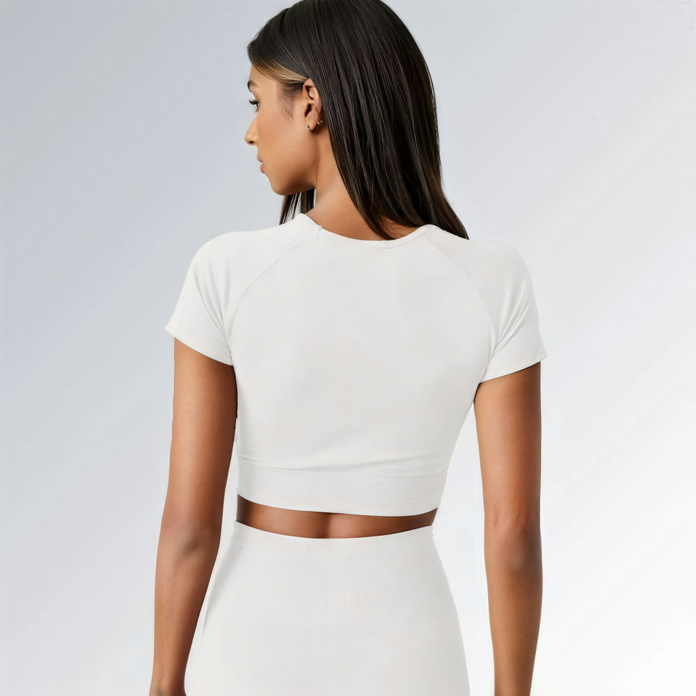 Top feminino branco sem costura, com mangas curtas, tecido canelado e caimento ajustado ao corpo.