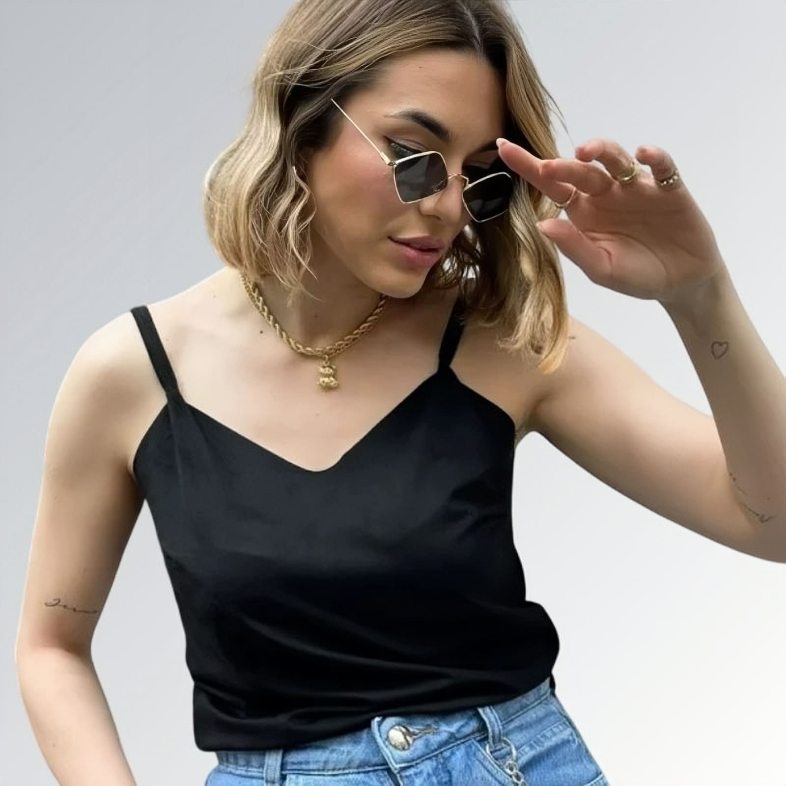 Blusa regata veludo estilo sueco feminina preta com alças finas, combinada com calça jeans azul clara e acessórios minimalistas — peça moderna disponível para venda online de moda casual.