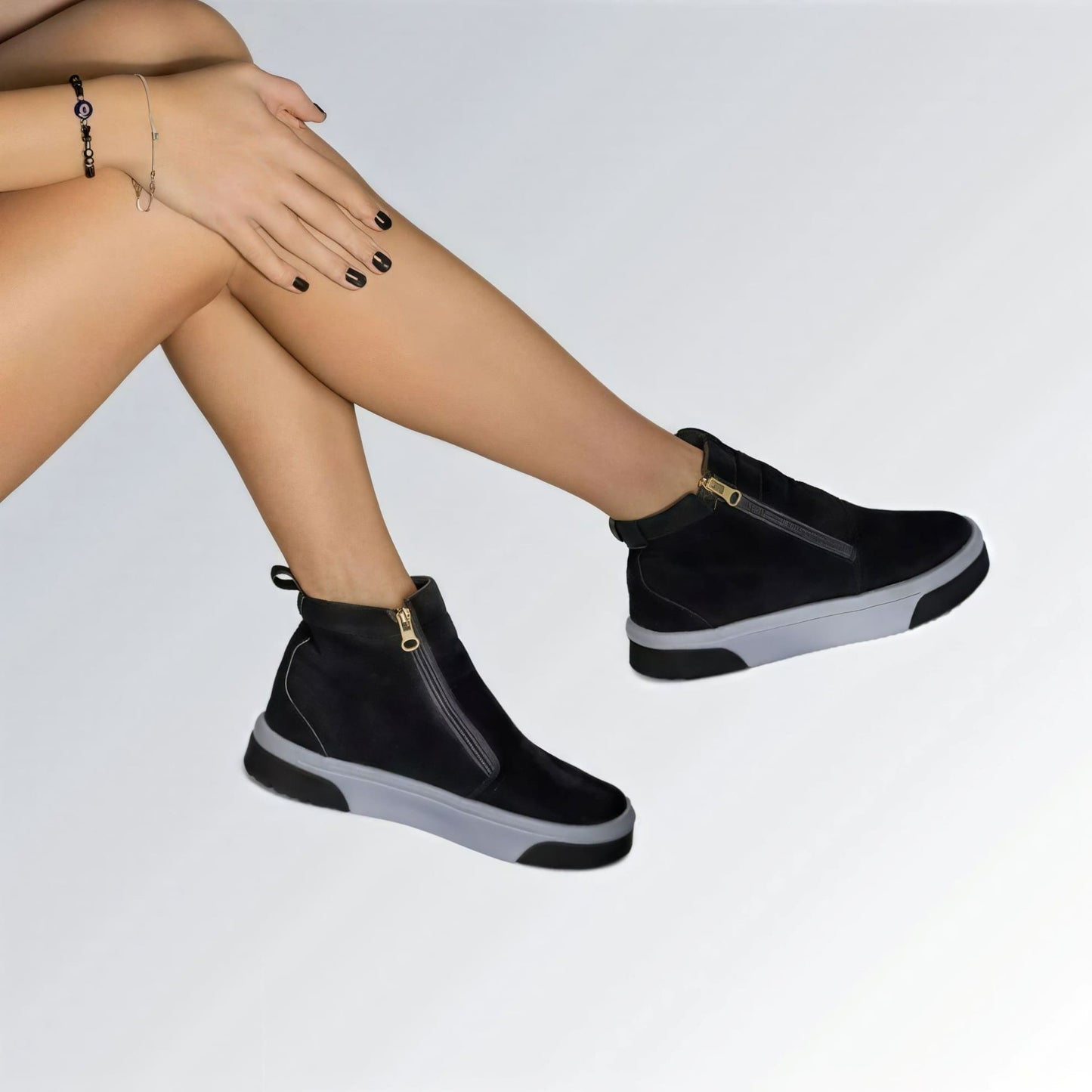 Bota feminina GuGi estilo Knot em camurça preta, com sola plana branca, zíper lateral e design moderno.