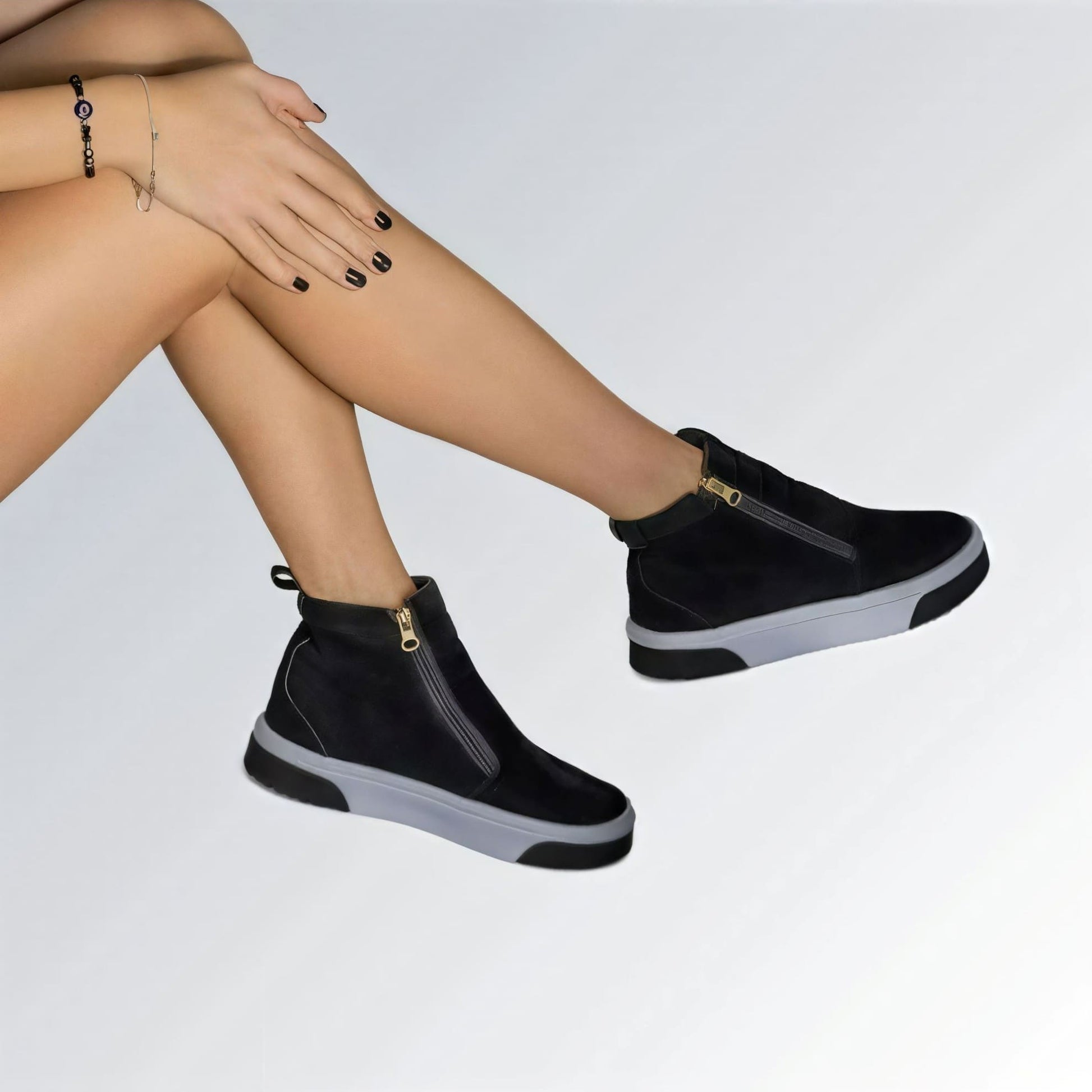 Bota feminina GuGi estilo Knot em camurça preta, com sola plana branca, zíper lateral e design moderno.