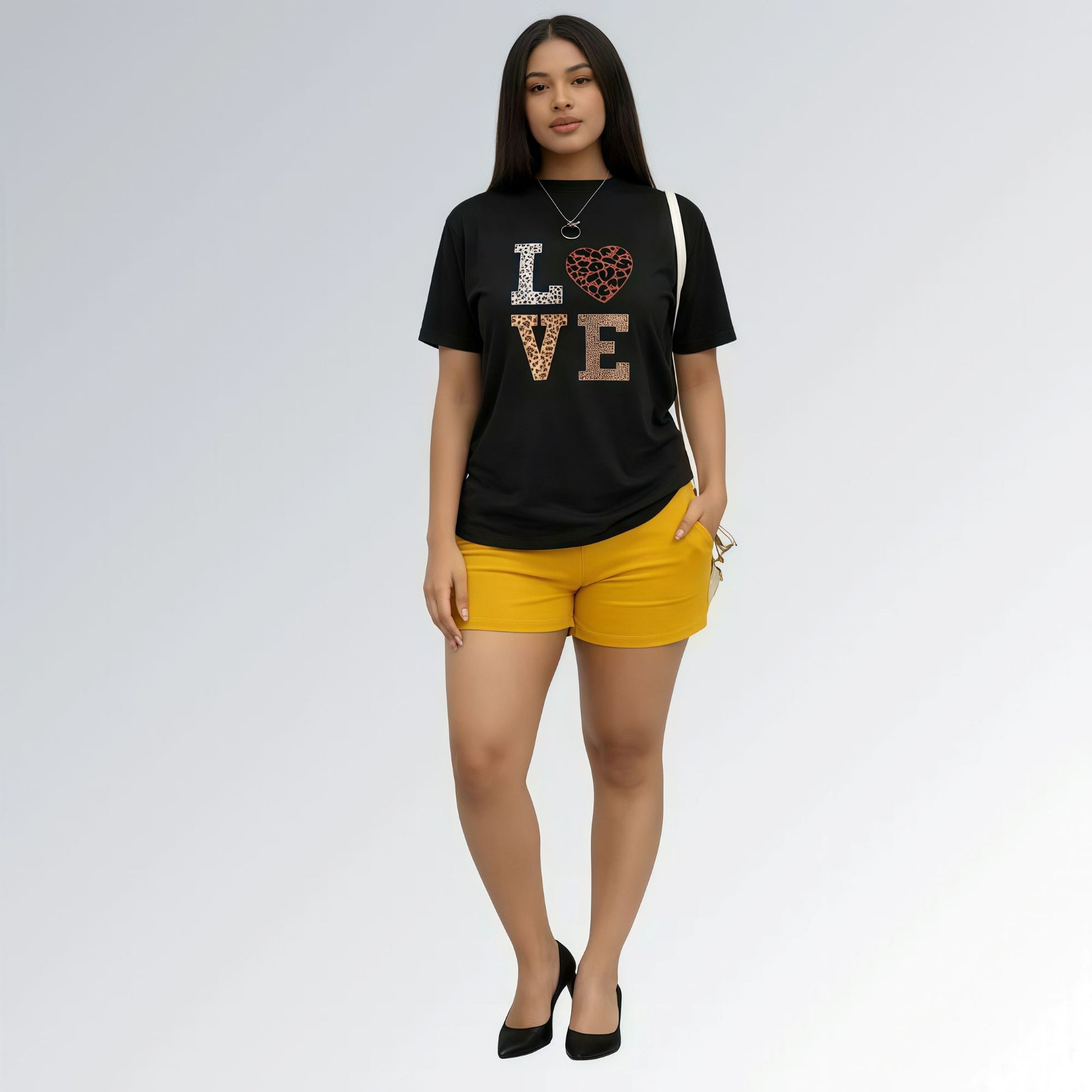 Modelo vestida com uma camisa preta feminina com estampa LOVE em animal print e shorts cor mostarda.