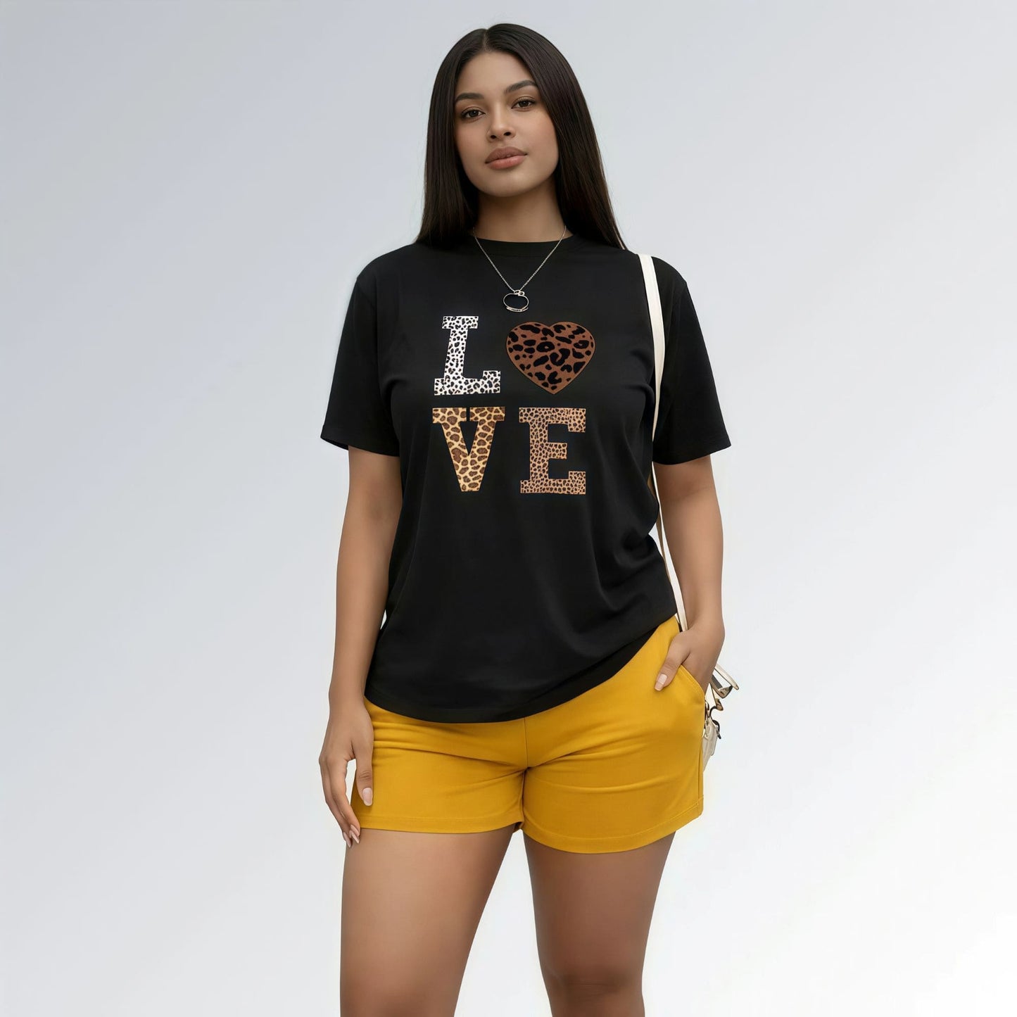 Modelo vestida com uma camisa preta feminina com estampa LOVE em animal print e shorts cor mostarda.