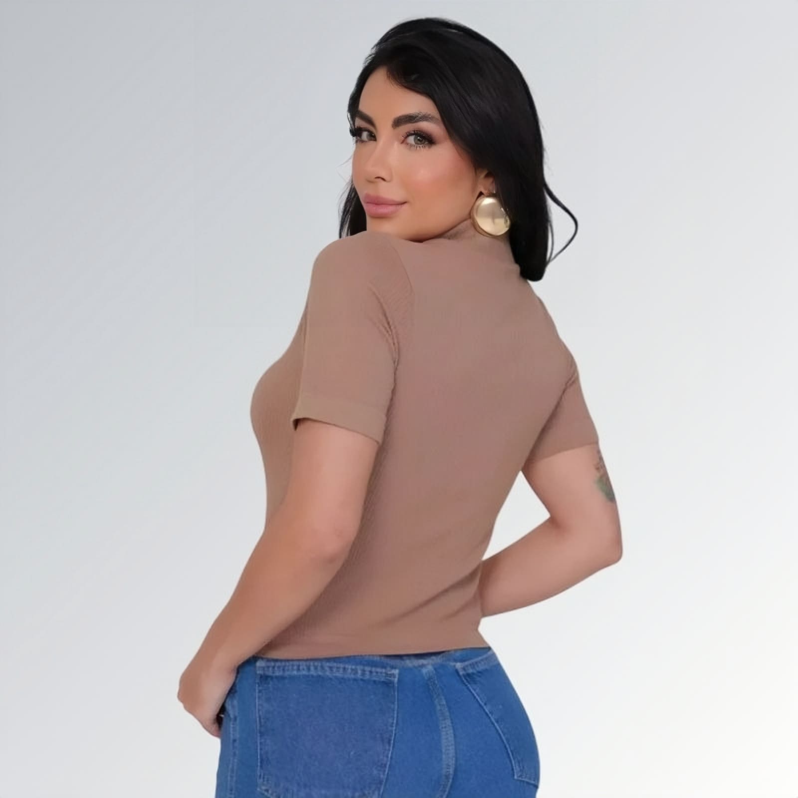 Camiseta manga curta gola alta parcial feminina champanhe ajustada, combinada com calça jeans cargo azul com bolsos laterais — peça moderna disponível para venda online de moda casual.