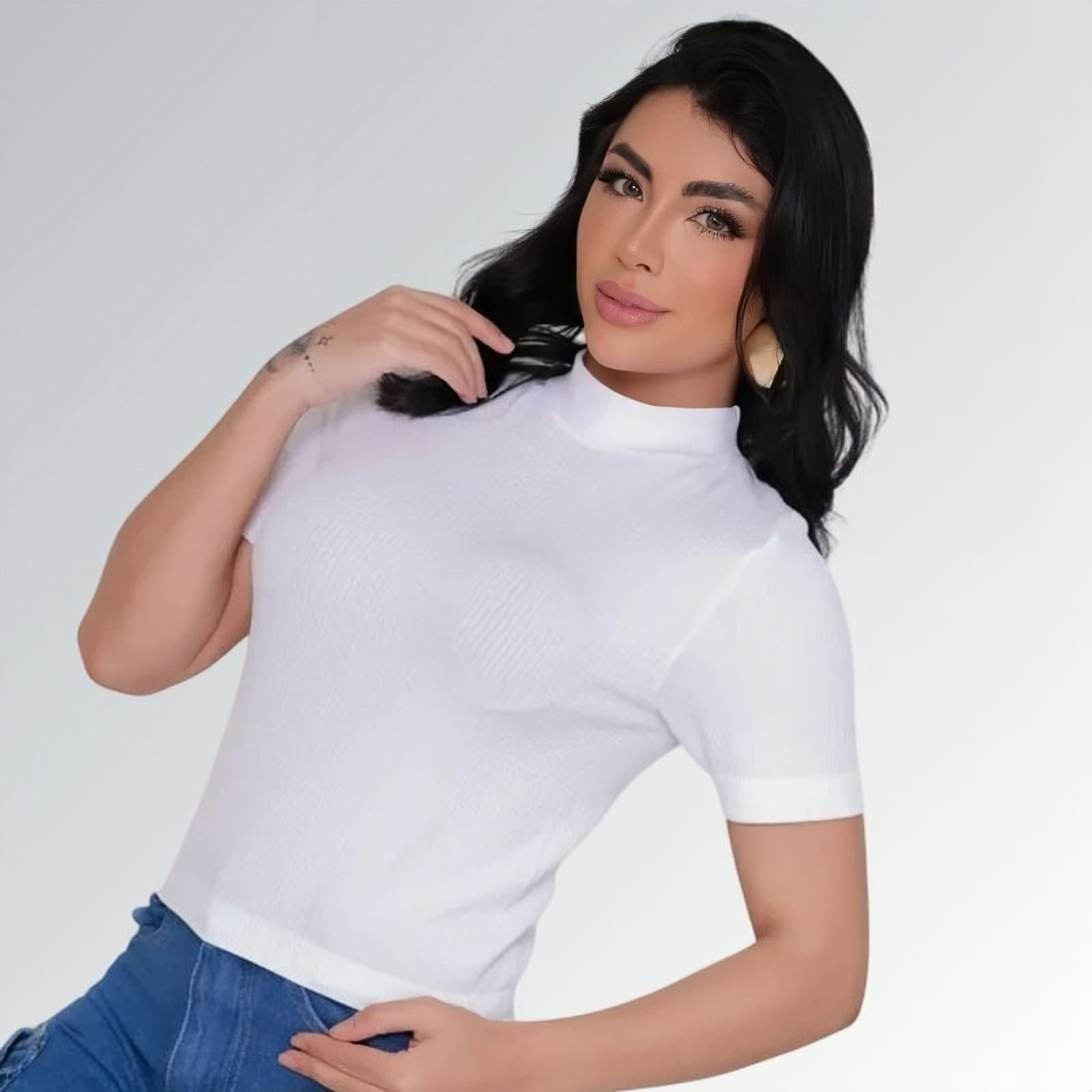 Camiseta manga curta gola alta parcial feminina branca ajustada, combinada com calça jeans cargo azul com bolsos laterais — peça moderna disponível para venda online de moda casual.