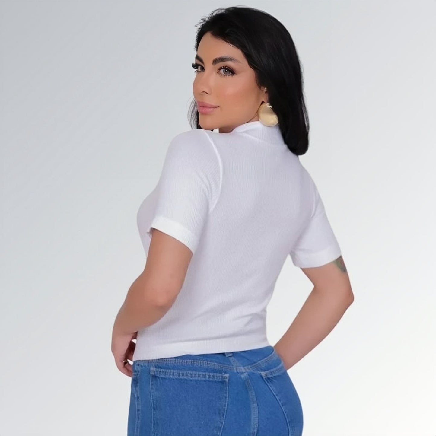 Camiseta manga curta gola alta parcial feminina branca ajustada, combinada com calça jeans cargo azul com bolsos laterais — peça moderna disponível para venda online de moda casual.