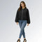 Mulher usando jaqueta feminina preta cropped com zíper metálico, mangas bufantes e calça jeans skinny, estilo casual moderno para o outono.