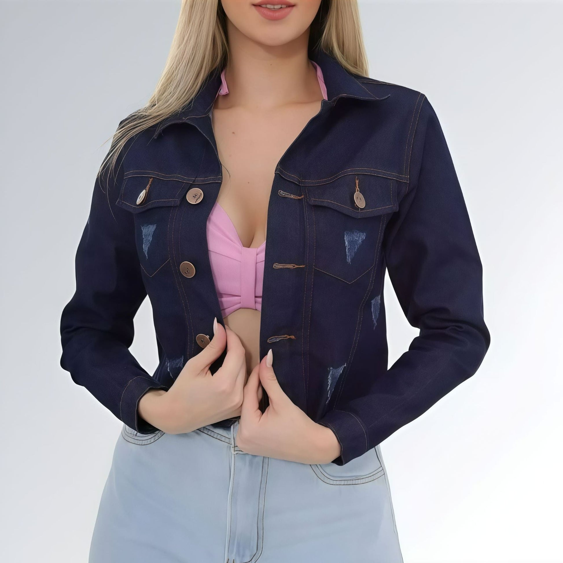 Jaqueta jeans cropped feminina azul escuro com puídos, bolsos frontais com aba e fechamento por botões.