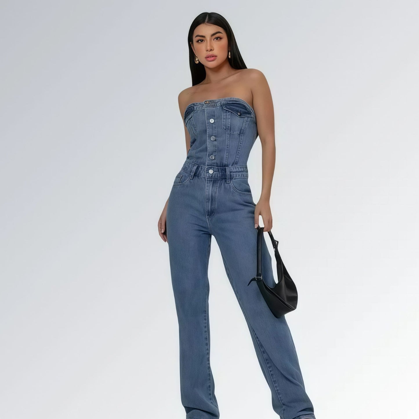 Macacão jeans feminino longo sem mangas com fechamento frontal por botões, cintura ajustada e pernas largas,  peça moderna disponível para venda online de moda casual e elegante.