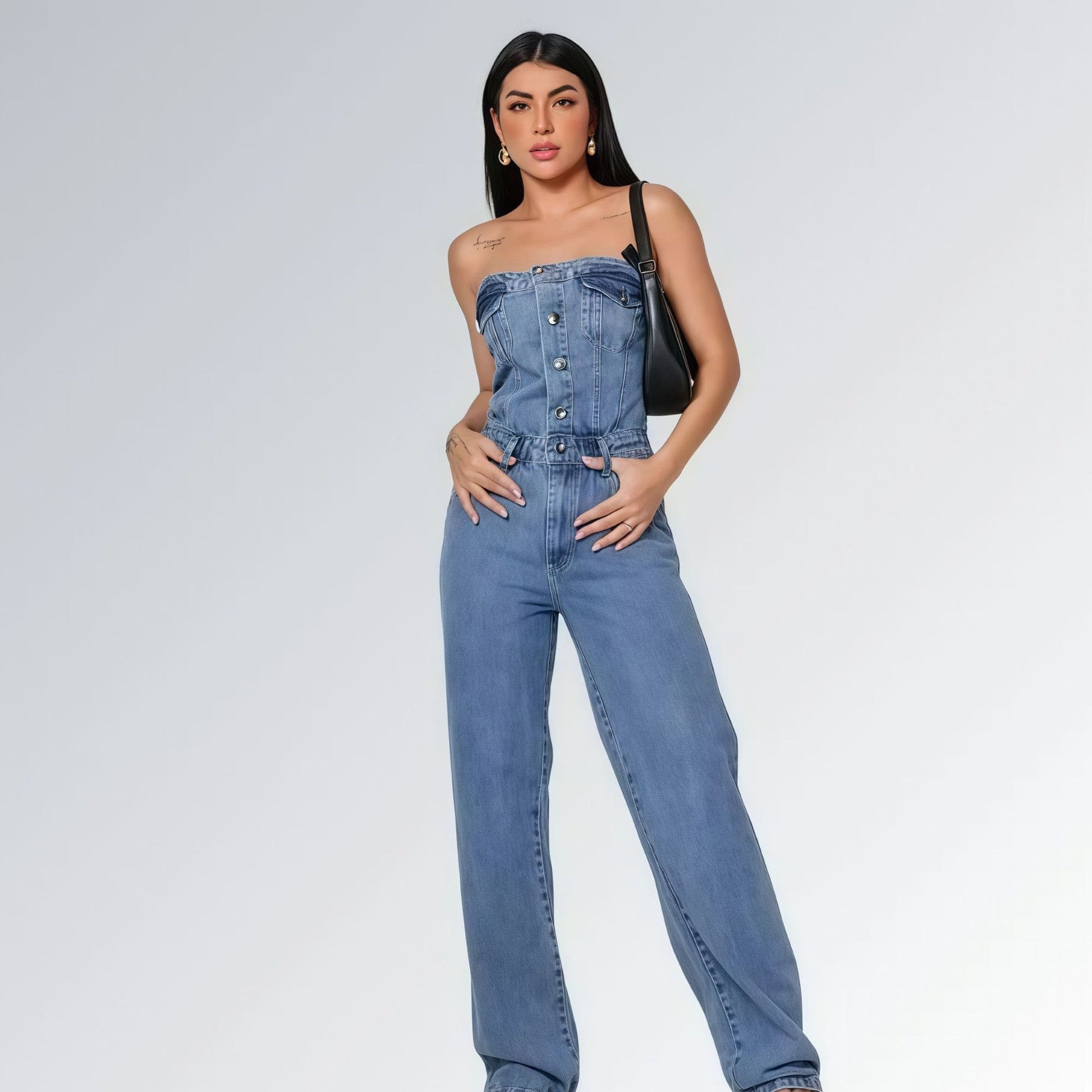 Macacão jeans feminino longo sem mangas com fechamento frontal por botões, cintura ajustada e pernas largas,  peça moderna disponível para venda online de moda casual e elegante.