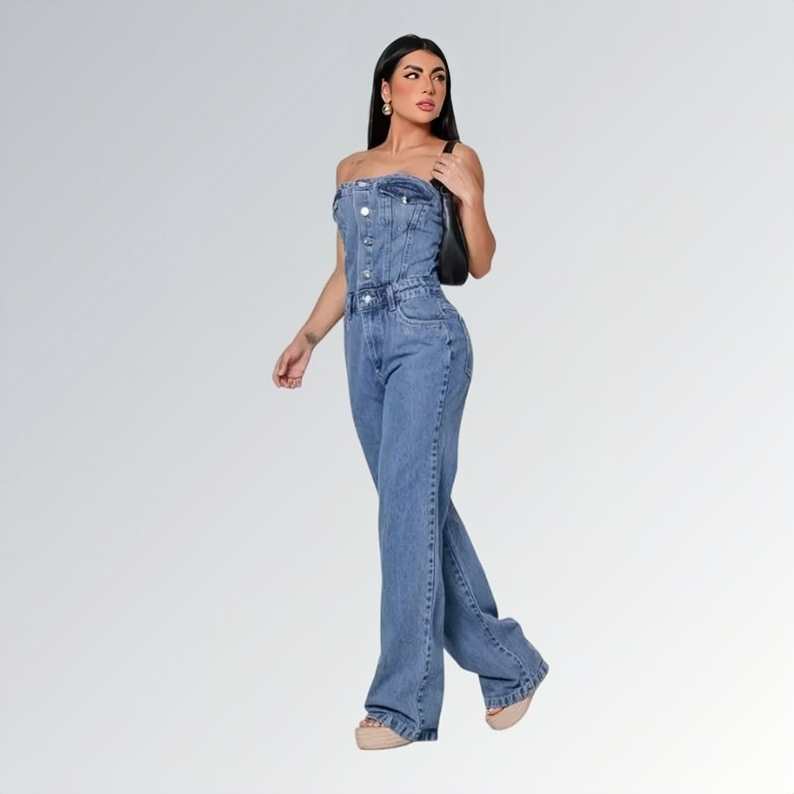 Macacão jeans feminino longo sem mangas com fechamento frontal por botões, cintura ajustada e pernas largas,  peça moderna disponível para venda online de moda casual e elegante.