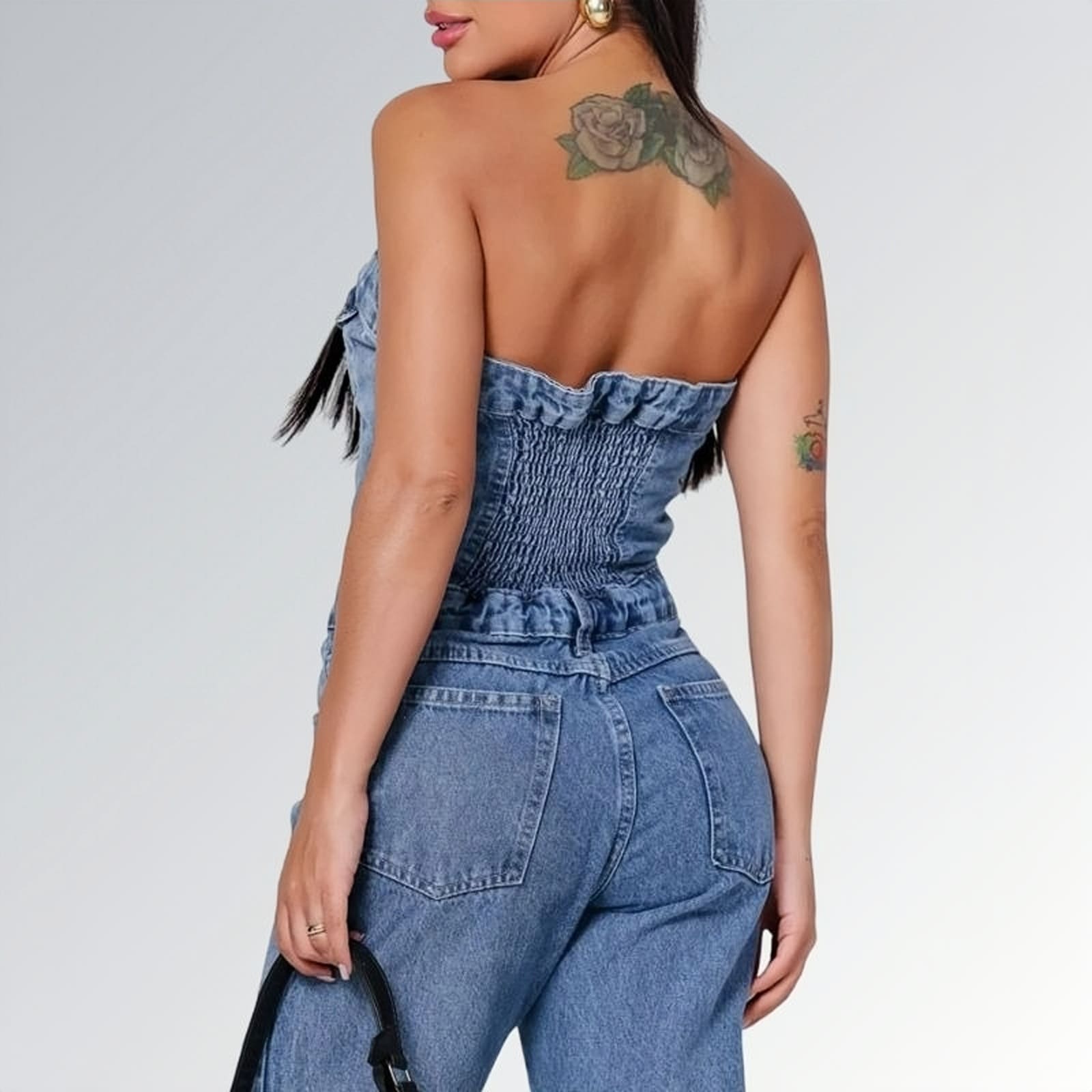Macacão jeans feminino longo sem mangas com fechamento frontal por botões, cintura ajustada e pernas largas,  peça moderna disponível para venda online de moda casual e elegante.