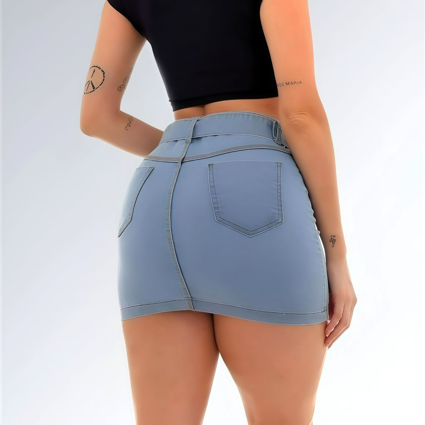 Mini saia jeans feminina azul clara com cintura alta, cinto com ilhós metálicos, bolsos frontais e leve desgaste na barra.