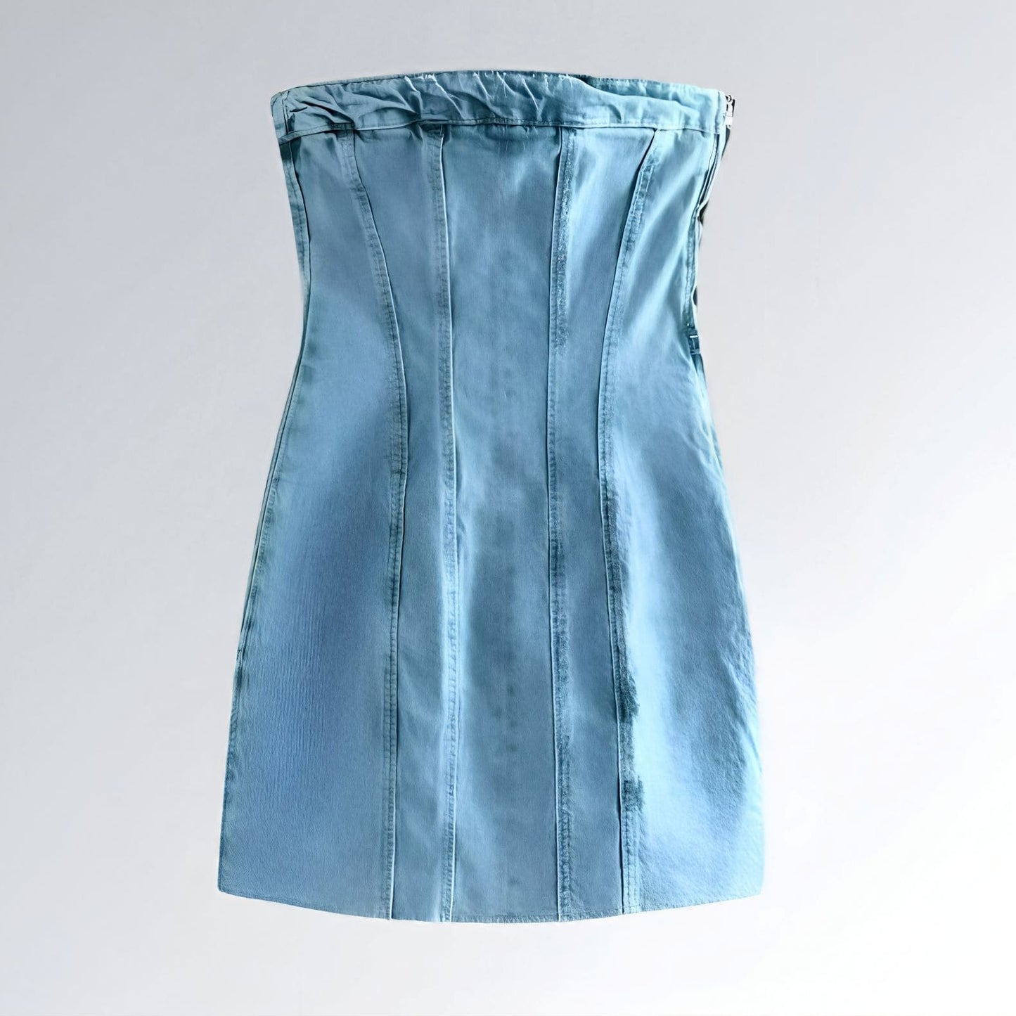 Mini vestido feminino jeans azul claro, modelo bodycon sem alças, com recortes verticais e acabamento franzido no busto.