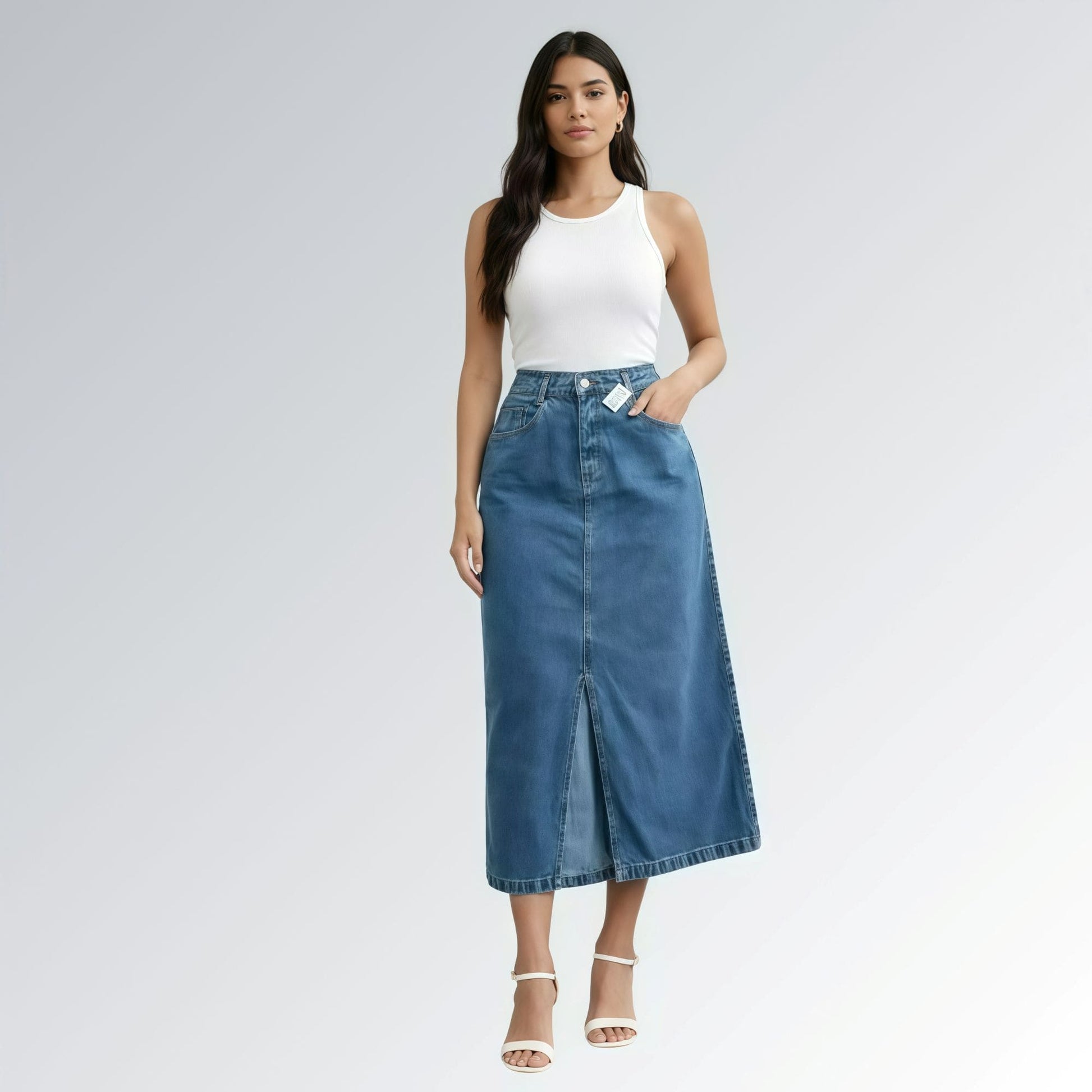 Saia jeans denim essential feminina azul com design clássico de cinco bolsos, fenda frontal e detalhe de costura central — peça versátil disponível para venda online de moda casual.