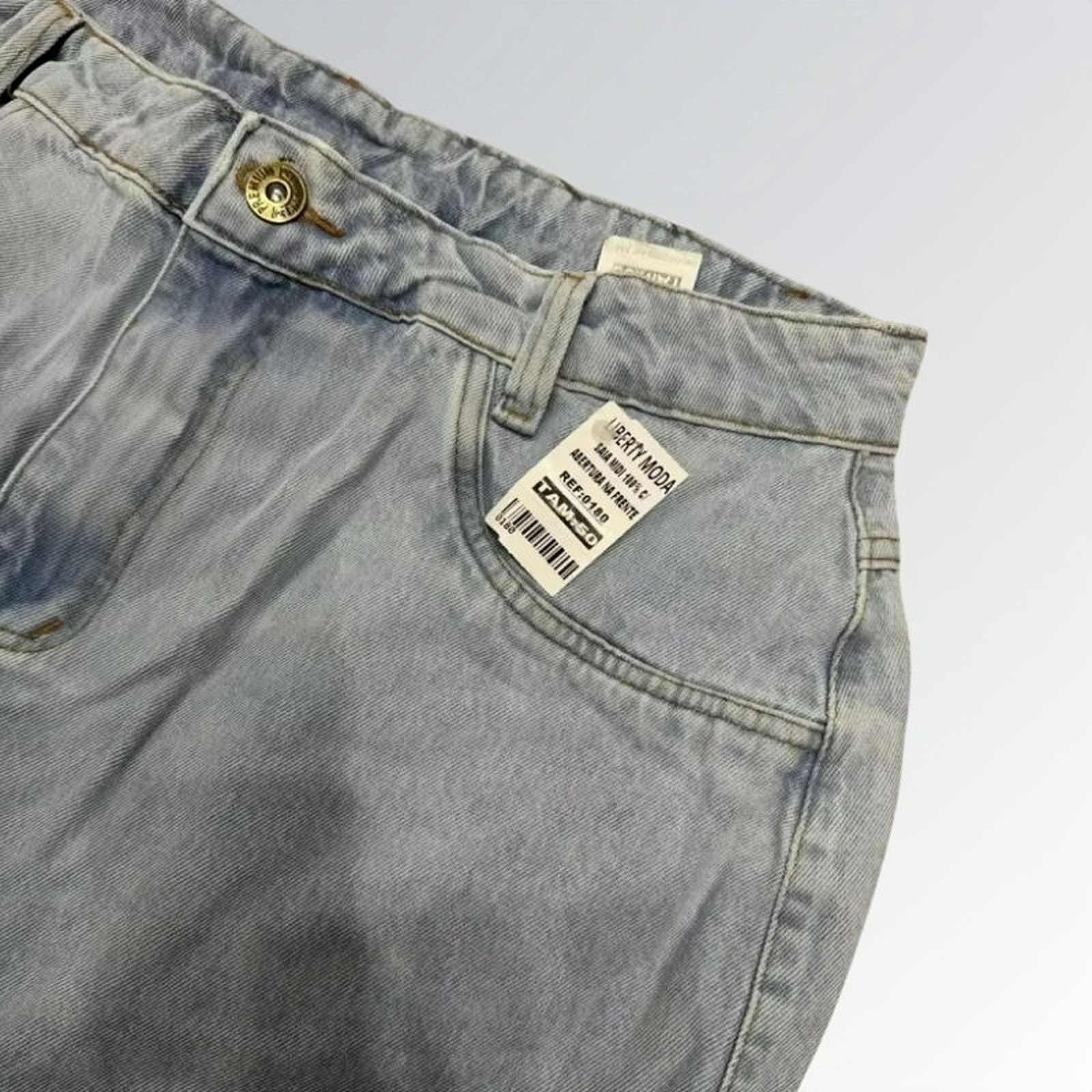Saia jeans denim essential feminina azul clara com design clássico de cinco bolsos, fenda frontal e detalhe de costura central — peça versátil disponível para venda online de moda casual.
