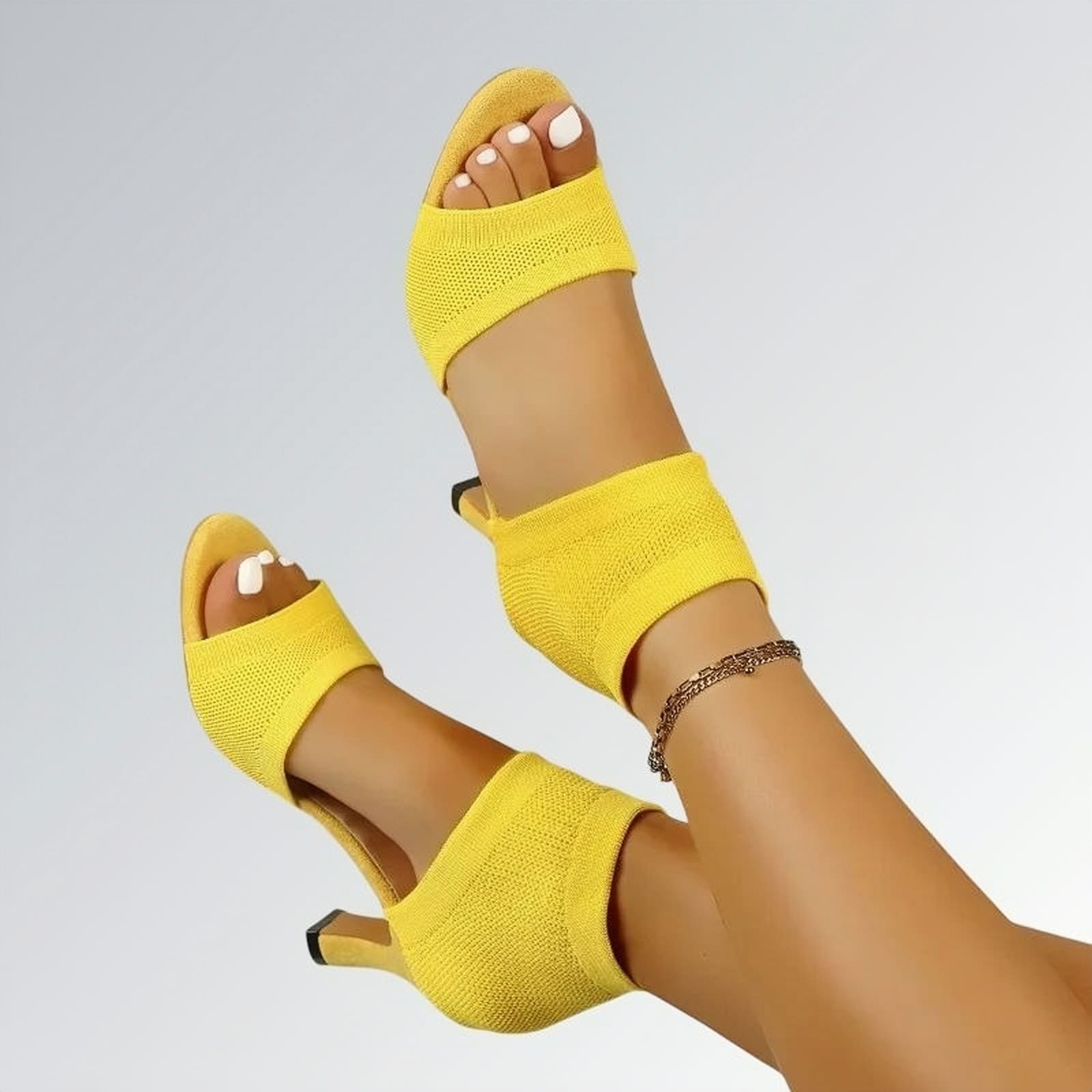 Sandália feminina salto alto fino slip on amarela com tira no calcanhar, textura em malha e design moderno de bico aberto — calçado elegante disponível para venda online.