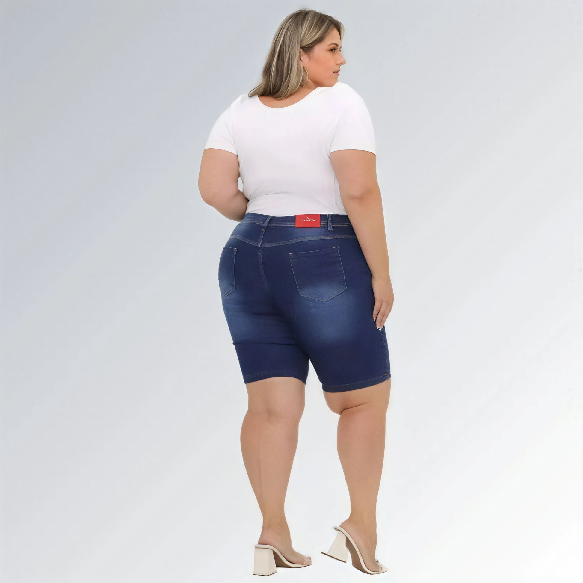Shorts jeans feminino plus size azul escuro, cintura alta, modelo premium com bolsos e costura aparente.