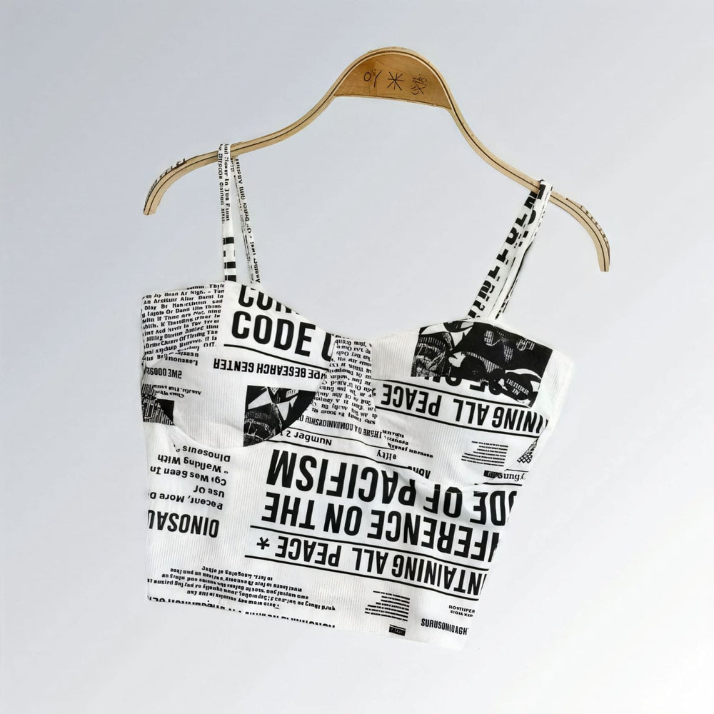 Top suspensório feminino cropped com bojo, estampa jornal preto e branco, alças largas e estilo urbano.