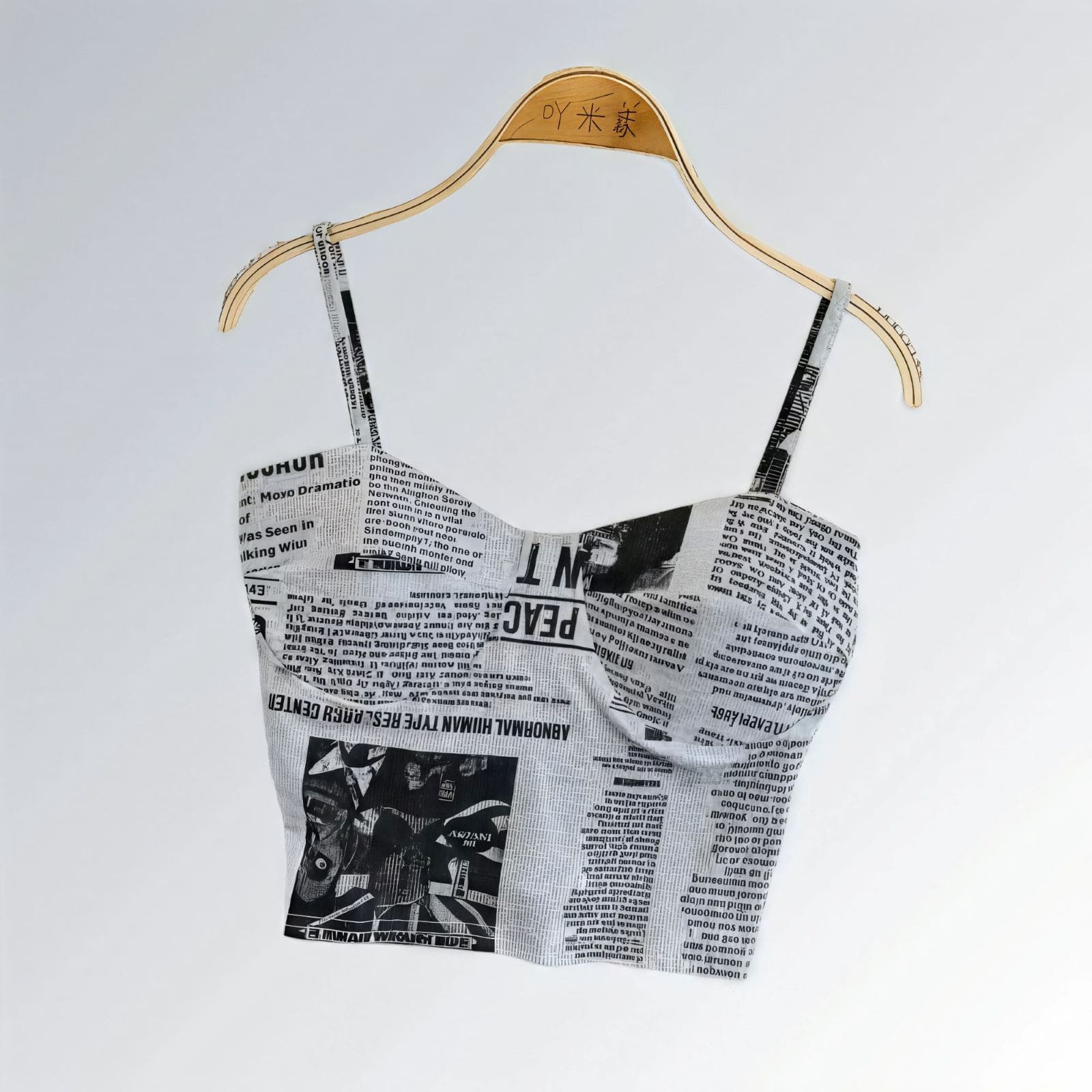Top suspensório feminino cropped com bojo, estampa jornal cinza e preto, alças largas e estilo urbano.
